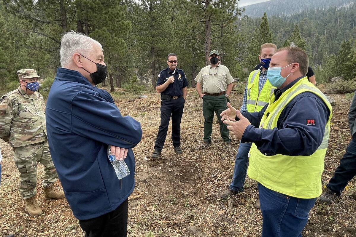 Gov. Steve Sisolak listens as NV Energy Fire Mitigation Specialist Mark Regan describes work be ...