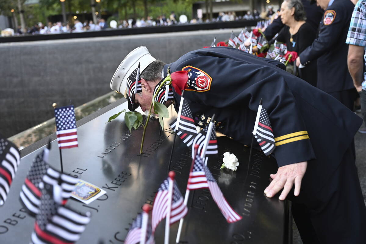 Retired Paramedic Chief Charlie Wells kisses the name of a relative killed in the attack on the ...