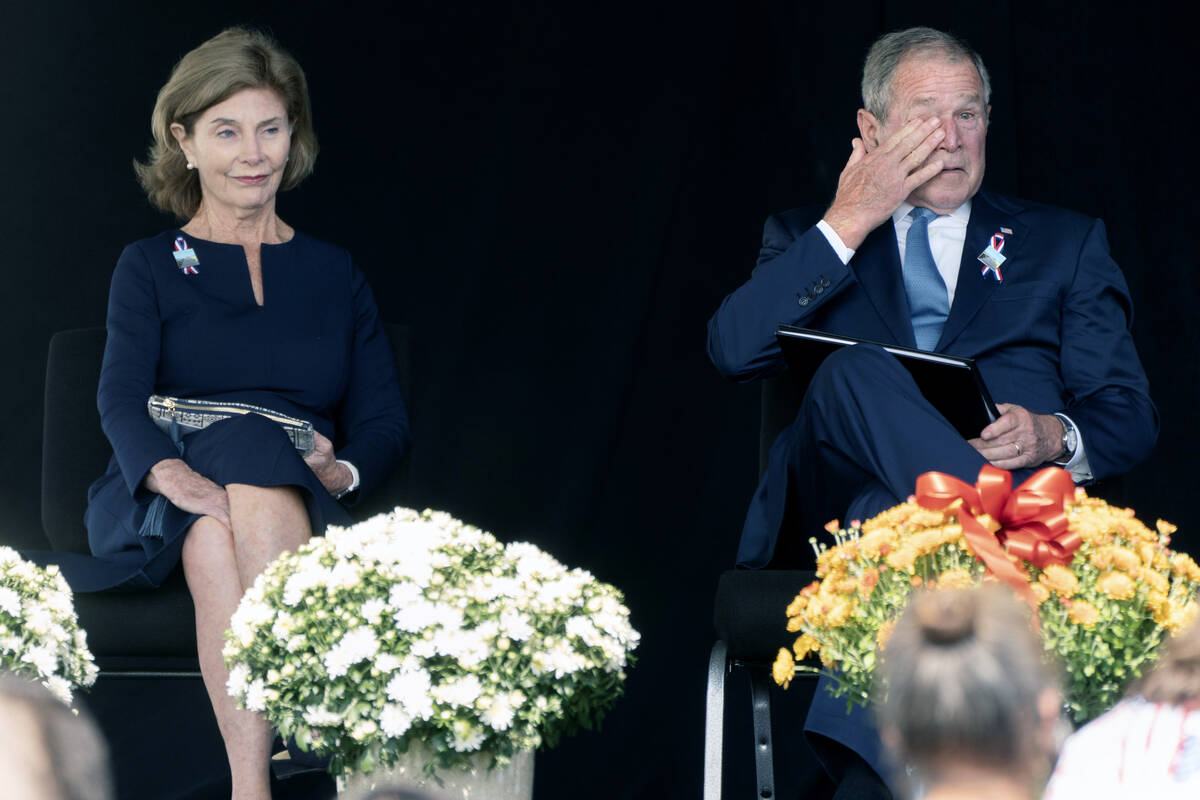Former President George W. Bush, right, wipes his eyes next to former first lady Laura Bush, af ...