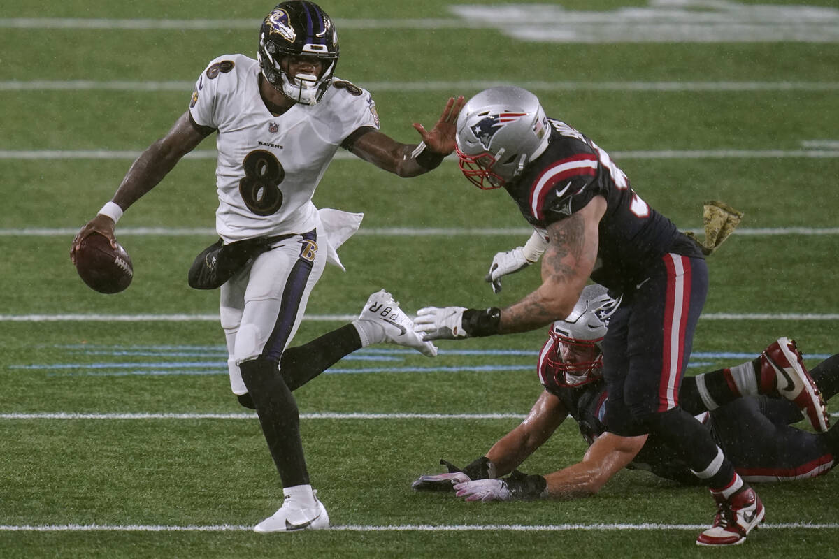 Baltimore Ravens quarterback Lamar Jackson, left, tries to elude New England Patriots defensive ...