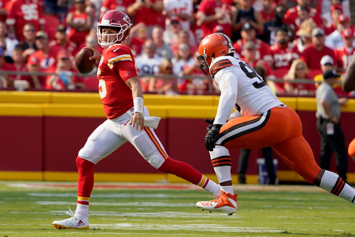 Kansas City Chiefs quarterback Patrick Mahomes, left, scrambles away from Cleveland Browns defe ...