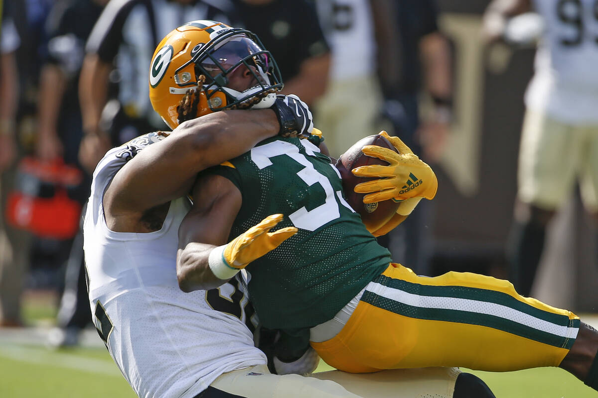 Green Bay Packers running back Aaron Jones, right, is stopped by New Orleans Saints defensive e ...