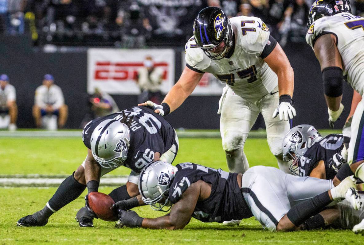 Raiders defensive tackle Darius Philon (96) picks up a fumble with teammate Raiders defensive e ...