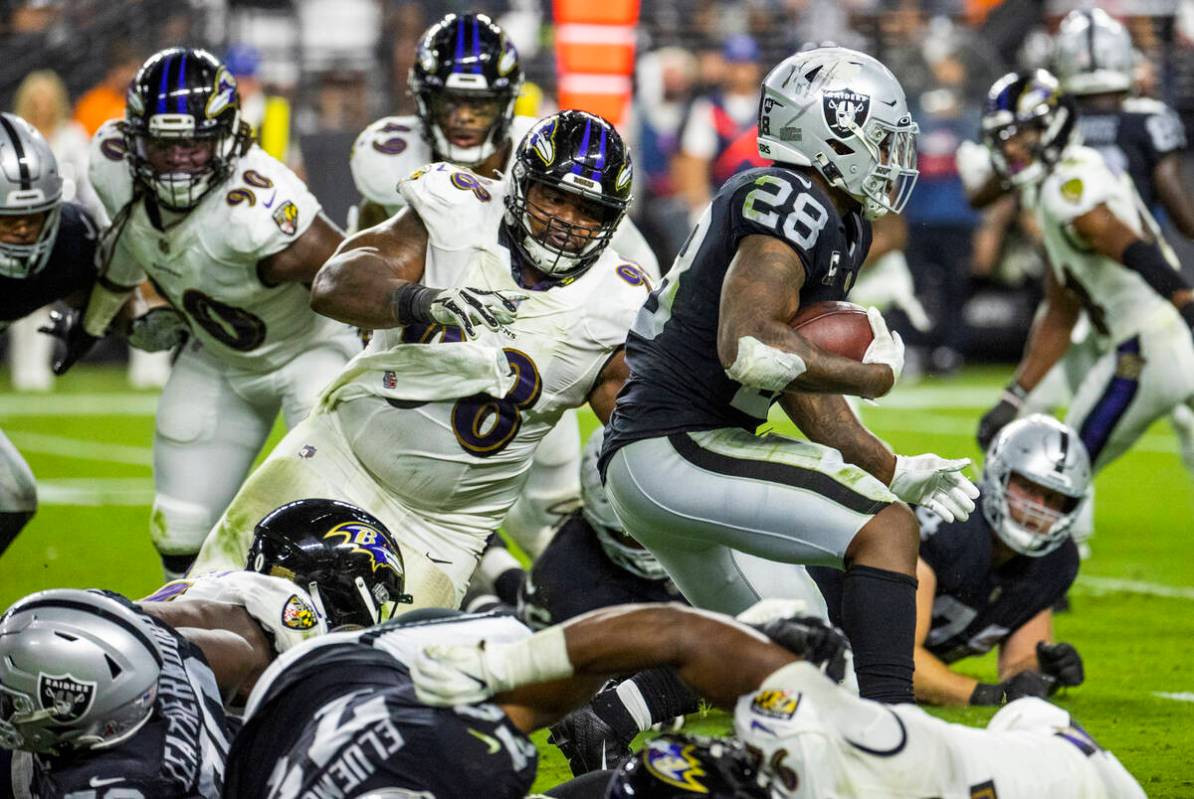 Raiders running back Josh Jacobs (28) heads towards the goal line as Baltimore Ravens defensive ...