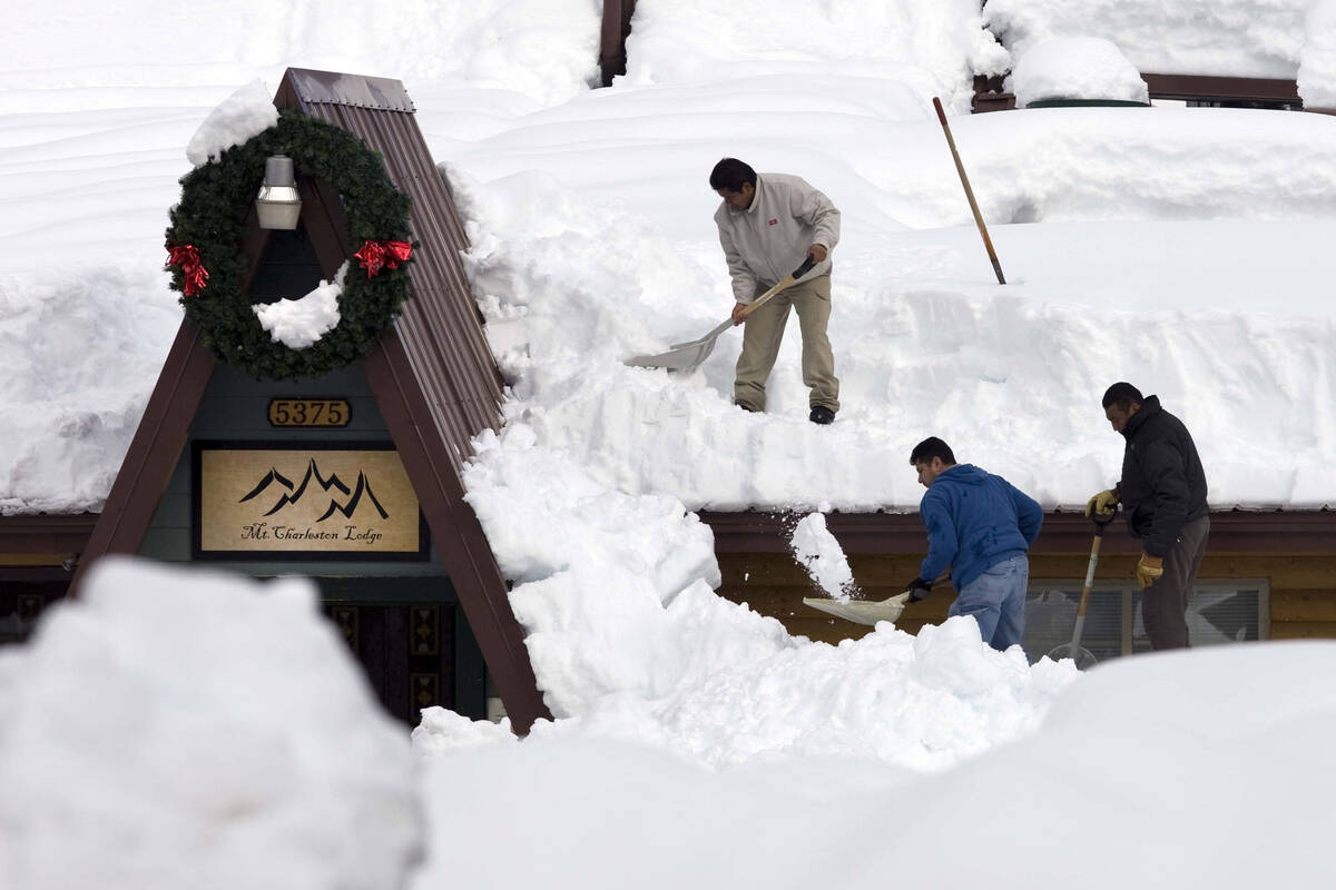 Workers, from left, Sergio Reyes, Manuel Franco, and Jose Trujillo shovel snow off the roof of ...
