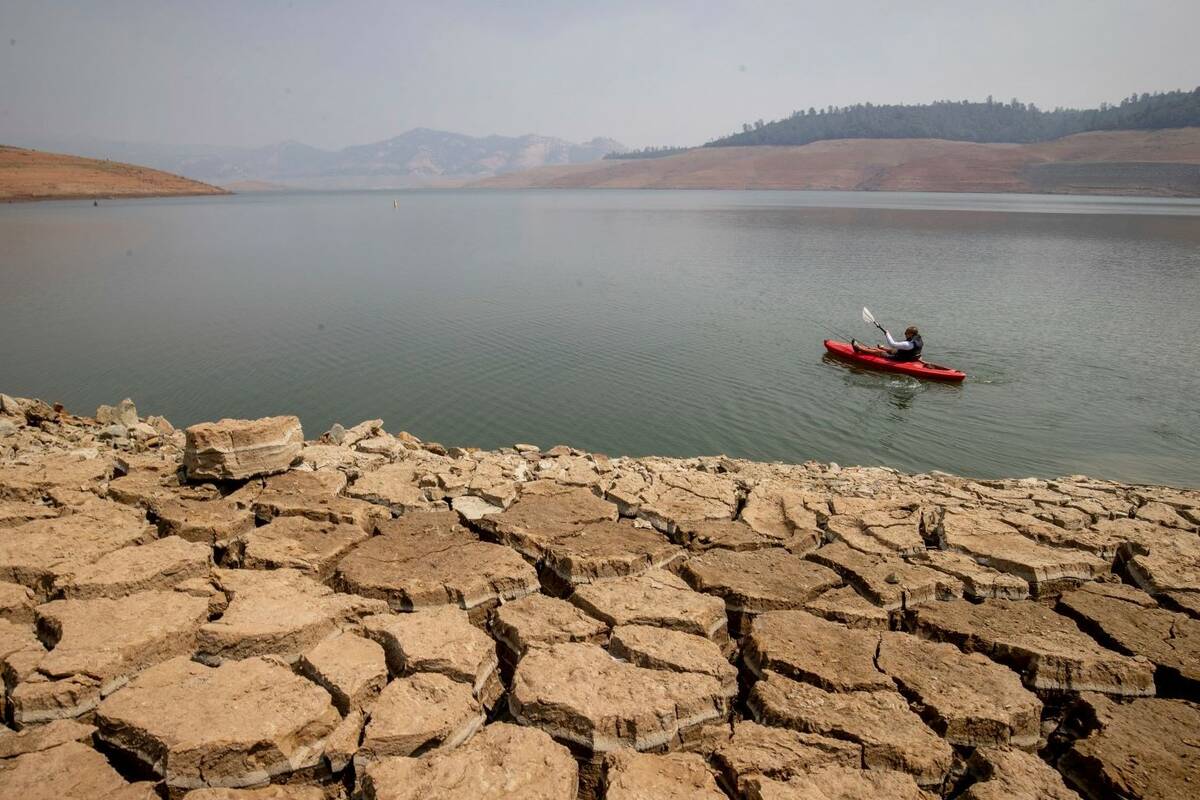 A kayaker fishes in Lake Oroville as water levels remain low due to continuing drought conditio ...