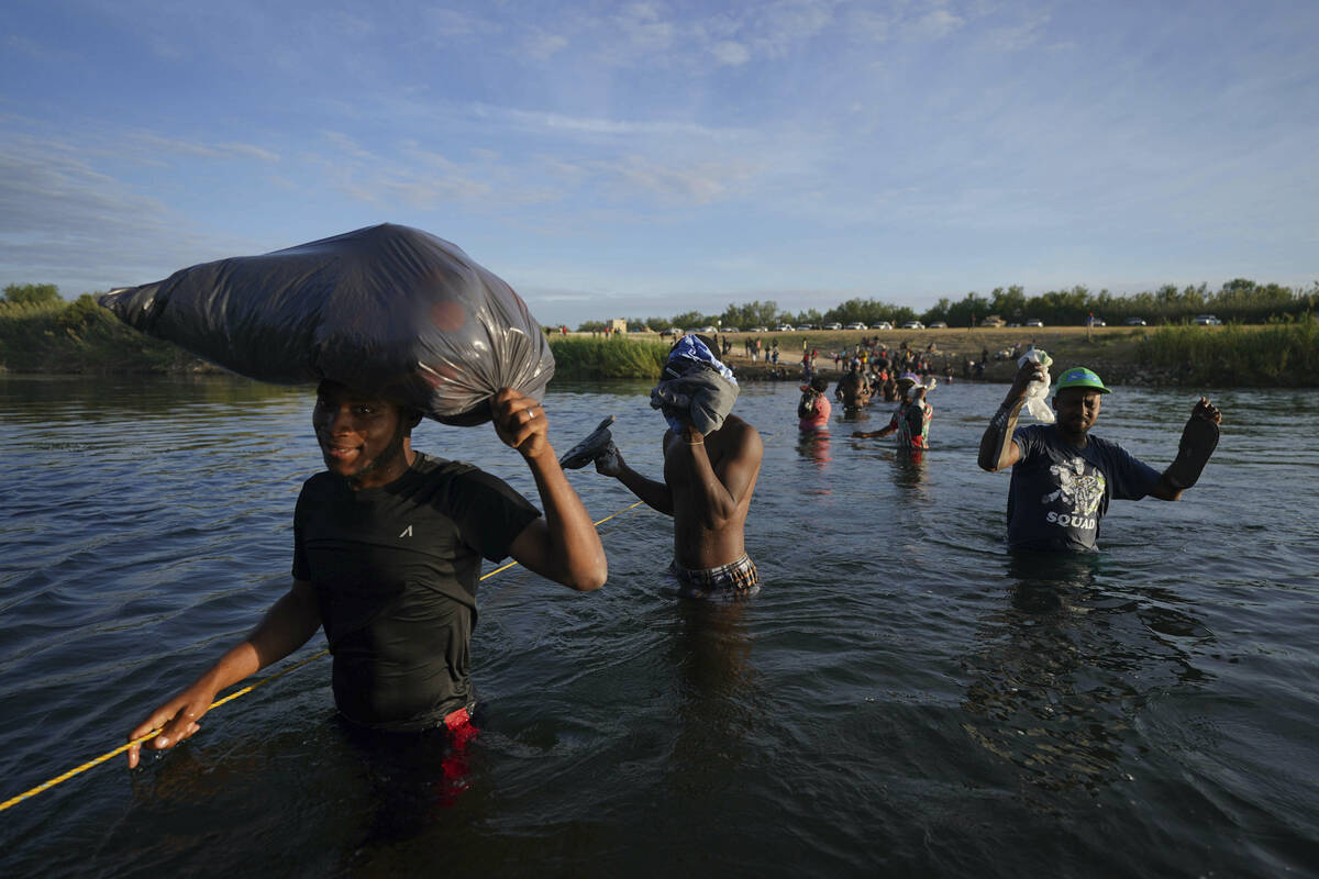 Migrants, many from Haiti, wade across the Rio Grande river to leave Del Rio, Texas, and return ...