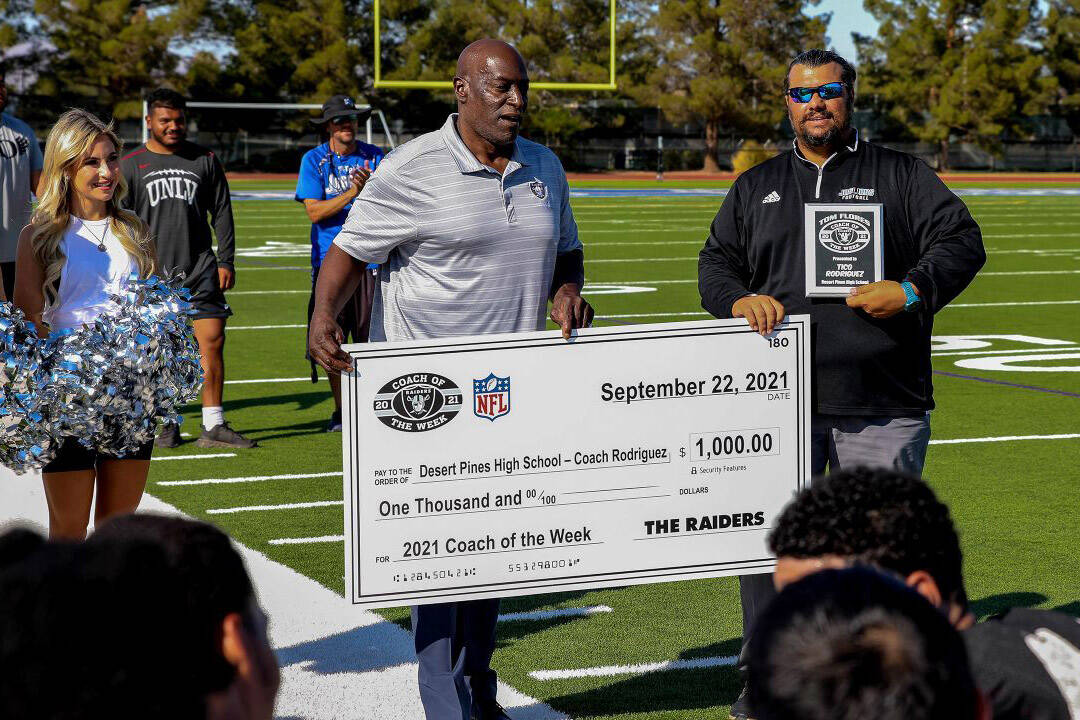 Former Raiders player Reggie Kinlaw, left, presents Desert Pines football coach Tico Rodriguez ...