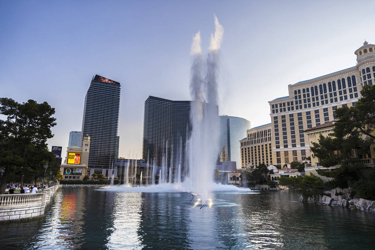 Pedestrians watch the fountain show with The Cosmopolitan of Las Vegas, left, and Bellagio in t ...