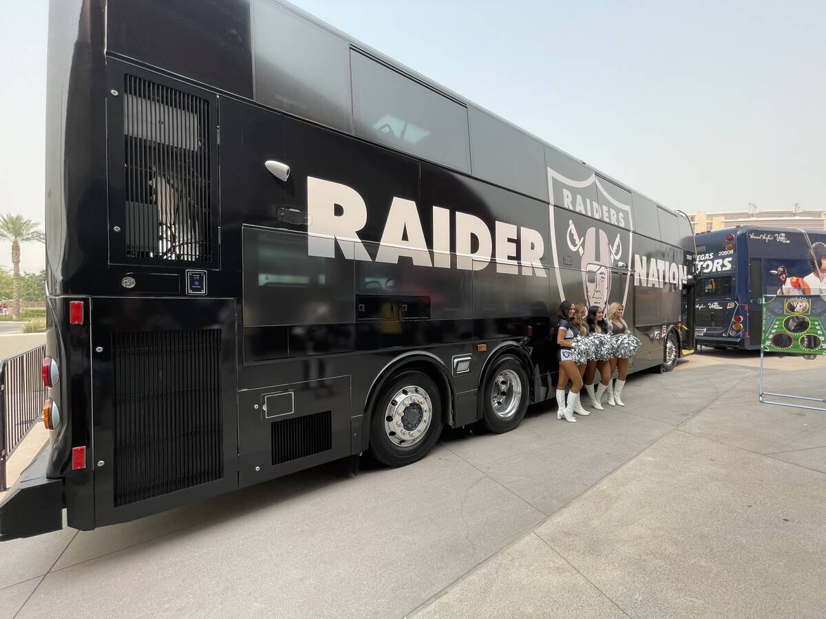 Three Raiderettes stand in front of RTC bus decked out in a Raiders wrap that is part of the RT ...