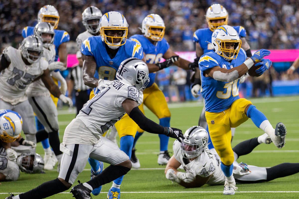 Los Angeles Chargers running back Austin Ekeler (30) bursts through the hole past Raiders corne ...