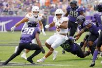 Texas running back Bijan Robinson (5) carries the the ball as a host of TCU defenders close in ...