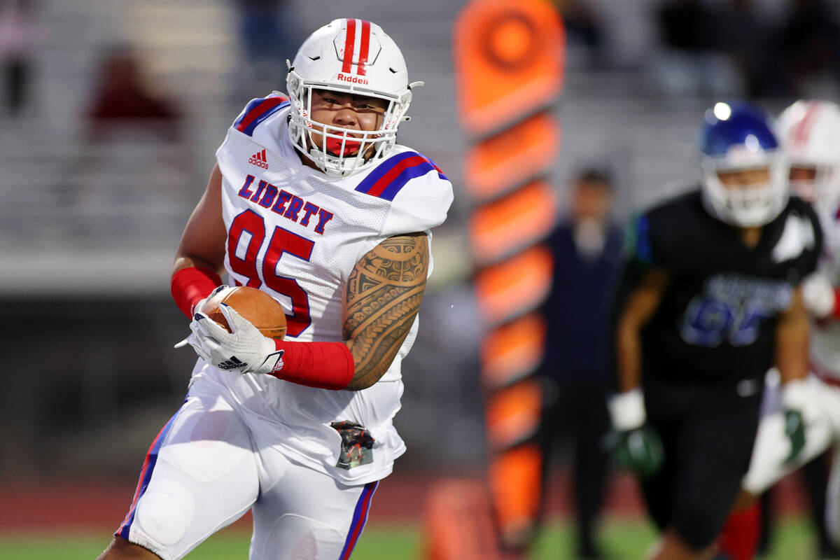 Liberty's Jayven Perez (95) runs the ball for a touchdown in the first half of a football game ...