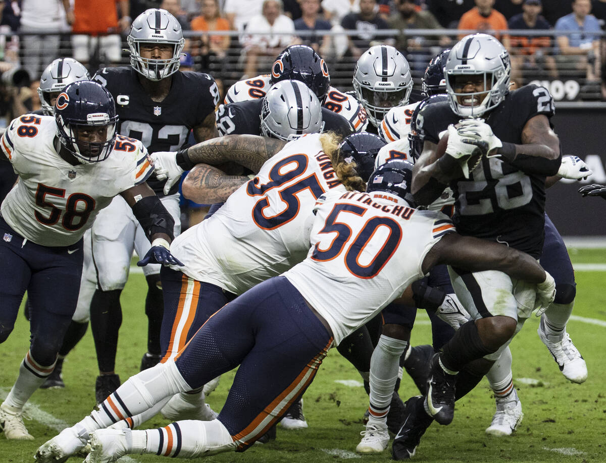 Raiders running back Josh Jacobs (28) tackled by the Chicago Bears defenders during the second ...