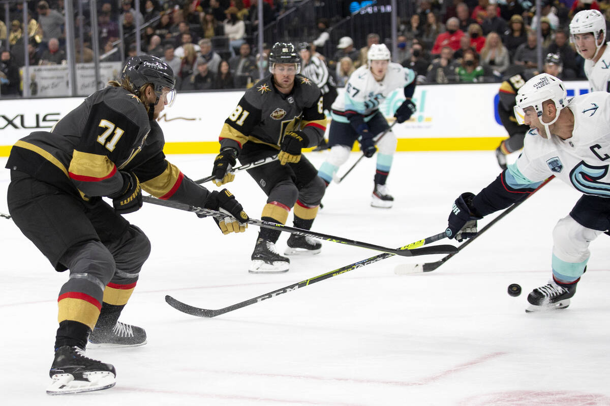 Golden Knights center William Karlsson (71) passes as Kraken defenseman Mark Giordano (5) reach ...