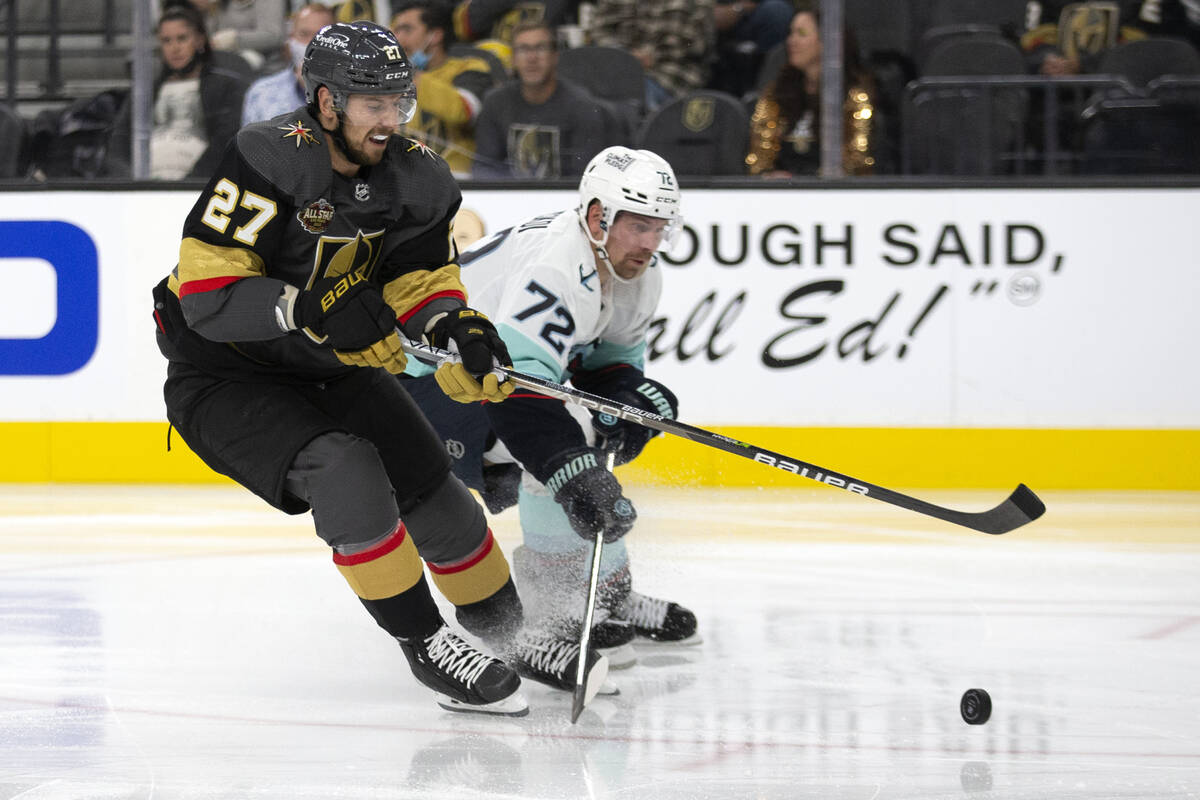 Golden Knights defenseman Shea Theodore (27) and Kraken right wing Joonas Donskoi (72) compete ...