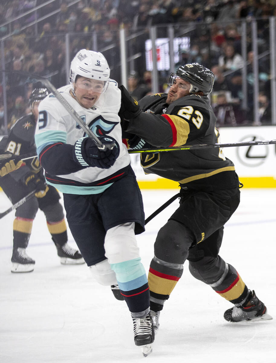 Golden Knights defenseman Alec Martinez (23) collides with Kraken center Ryan Donato (9) in the ...