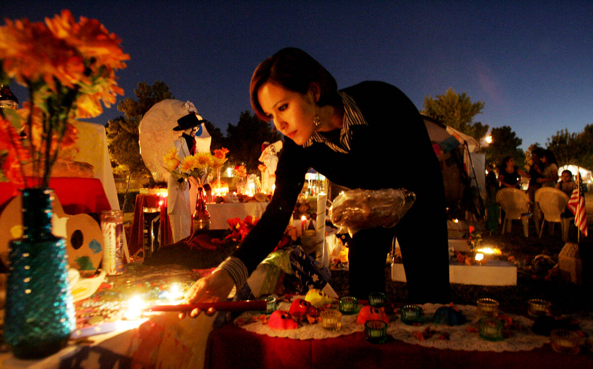 RJ FILE*** CRAIG L. MORAN/REVIEW-JOURNAL Claudia Sanchez lights candles on an "ofrenda,& ...