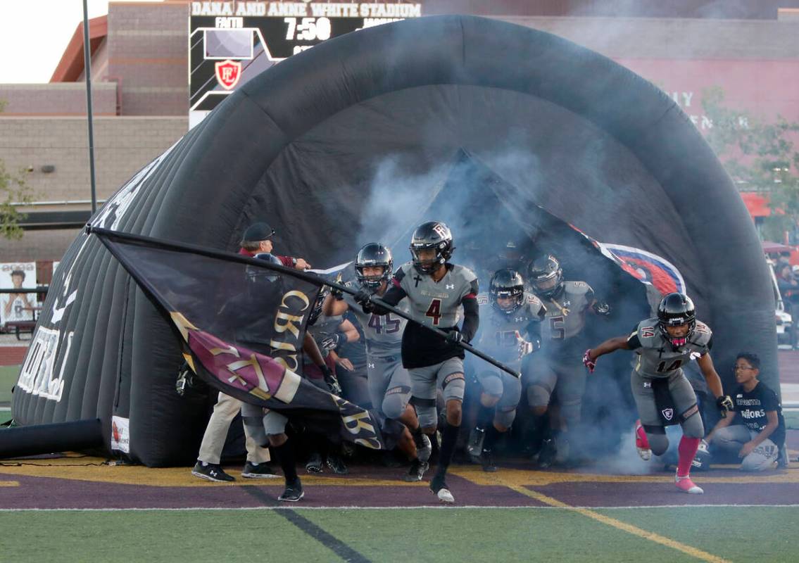 Faith Lutheran School's players run out to the field before a football game against Desert Pine ...