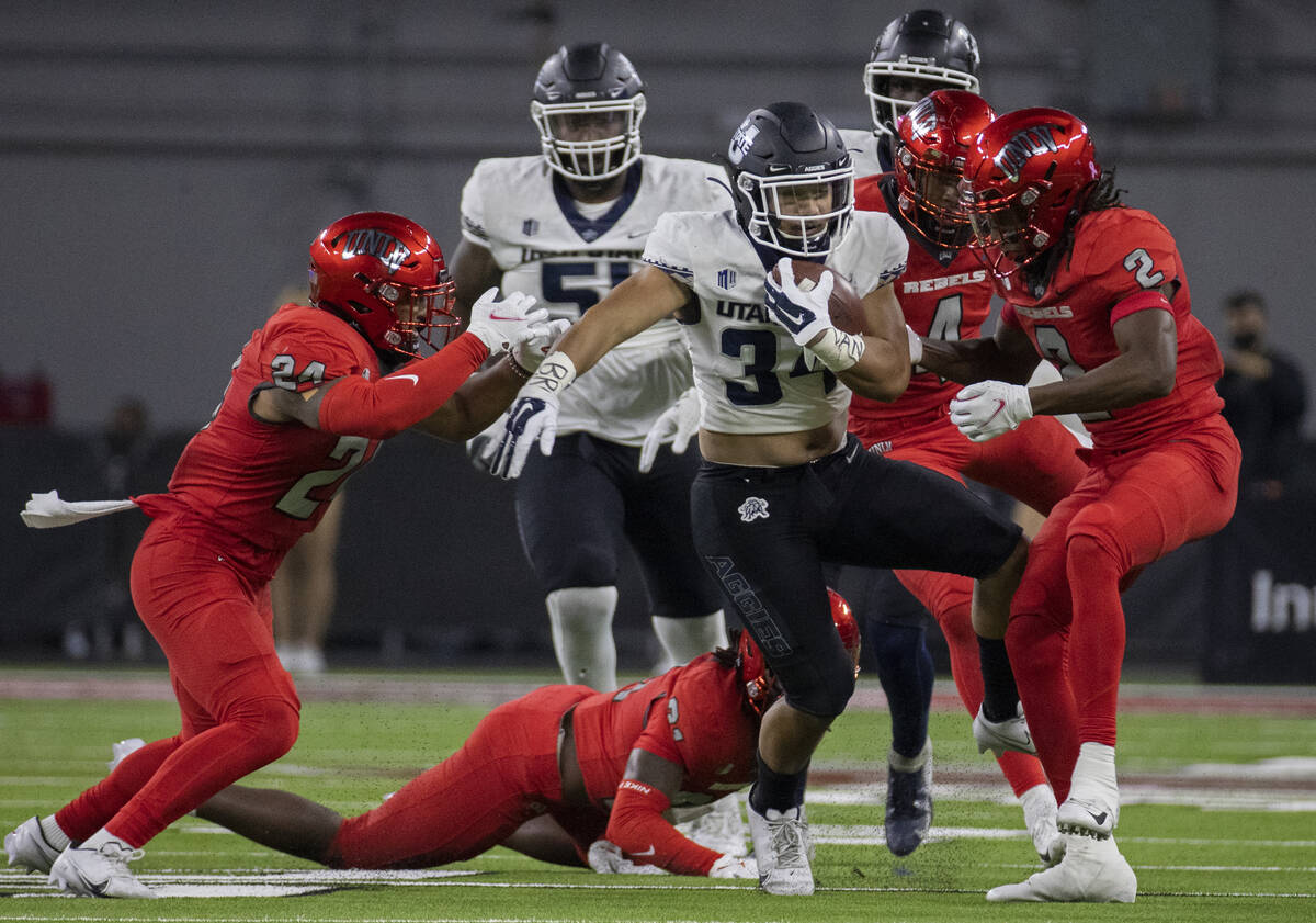 Utah State Aggies running back Elelyon Noa (34) fights for extra yardage past UNLV Rebels defen ...