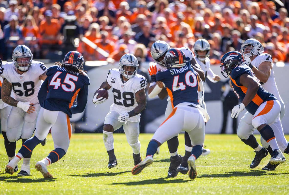 Raiders running back Josh Jacobs (28) looks to a hole in the offensive line versus the Denver B ...