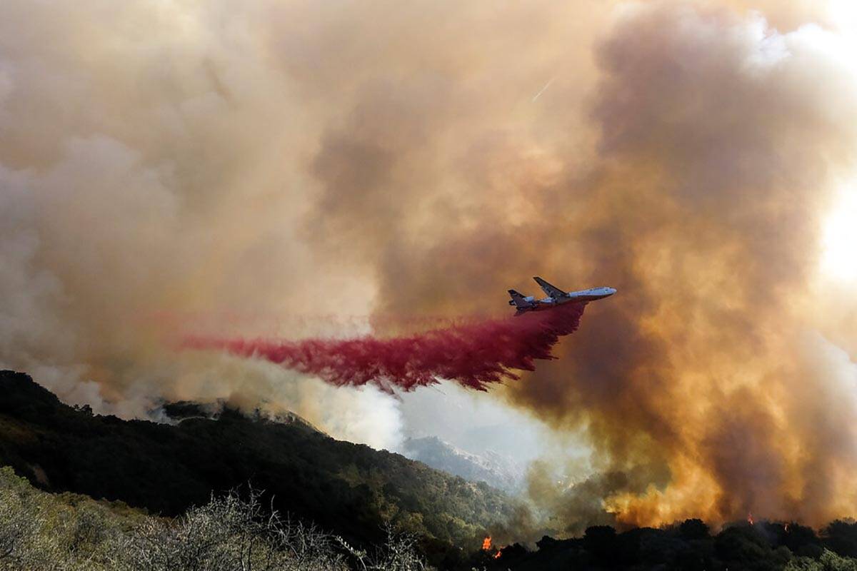 In this Oct. 13, 2021, file photo, an air tanker drops retardant on a wildfire in Goleta, Calif ...