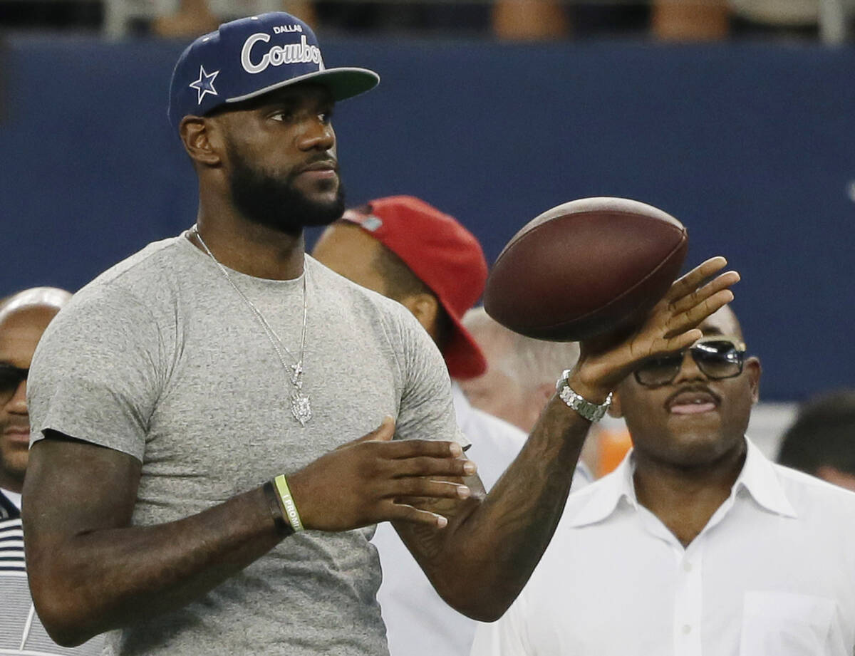 NBA basketball player LeBron James tosses a ball around before an NFL football game between the ...
