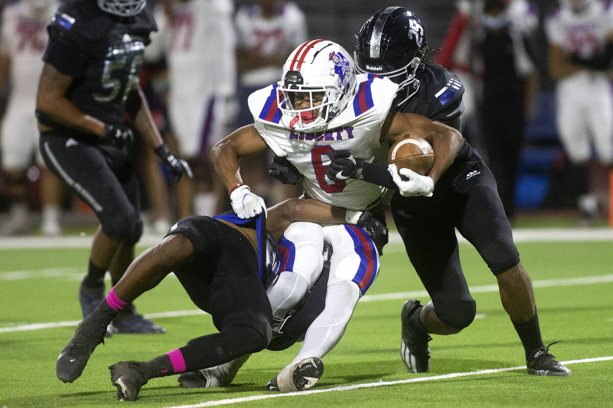 Liberty's Anthony Jones (6) is taken down by Desert Pines' Jett Solomon (4) and Landon Mccomber ...