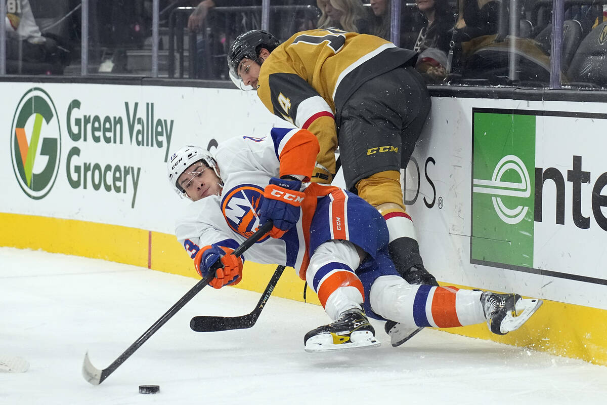 Vegas Golden Knights defenseman Nicolas Hague, top, checks New York Islanders center Mathew Bar ...