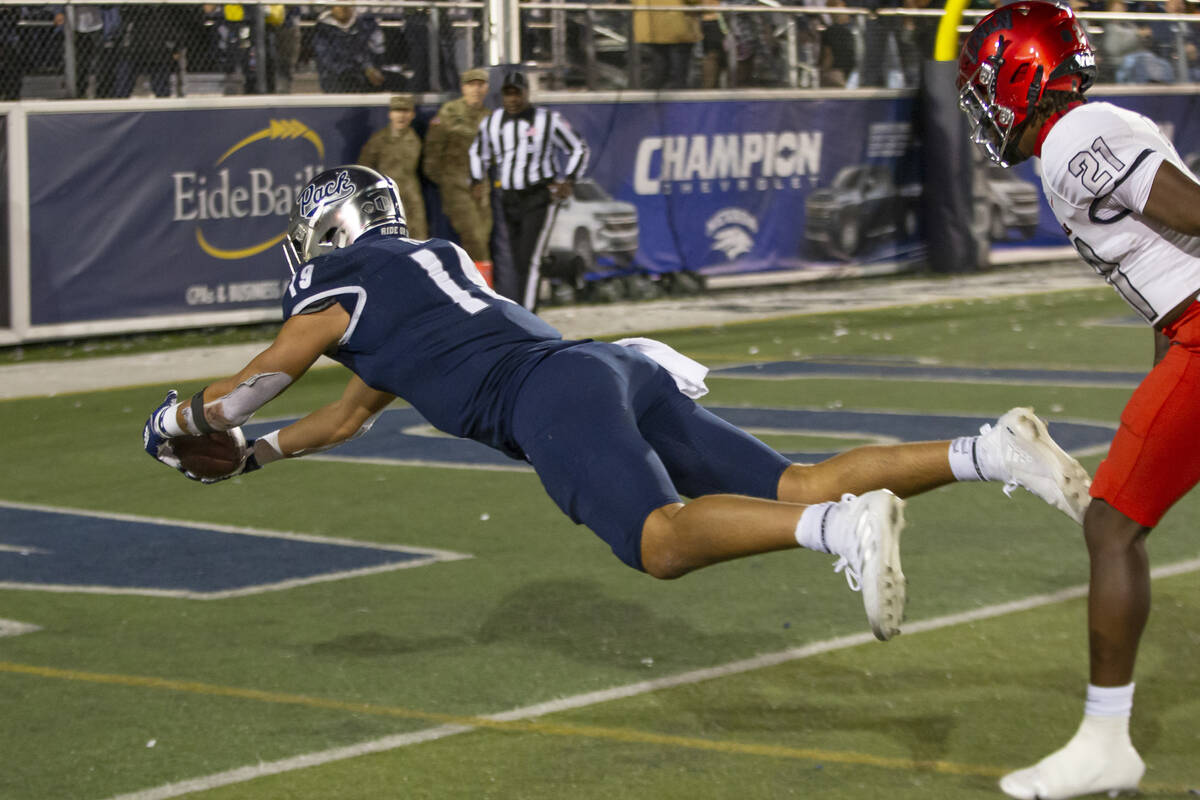 Nevada tight end Cole Turner (19) dives into the end zone for a touchdown in front of UNLV defe ...