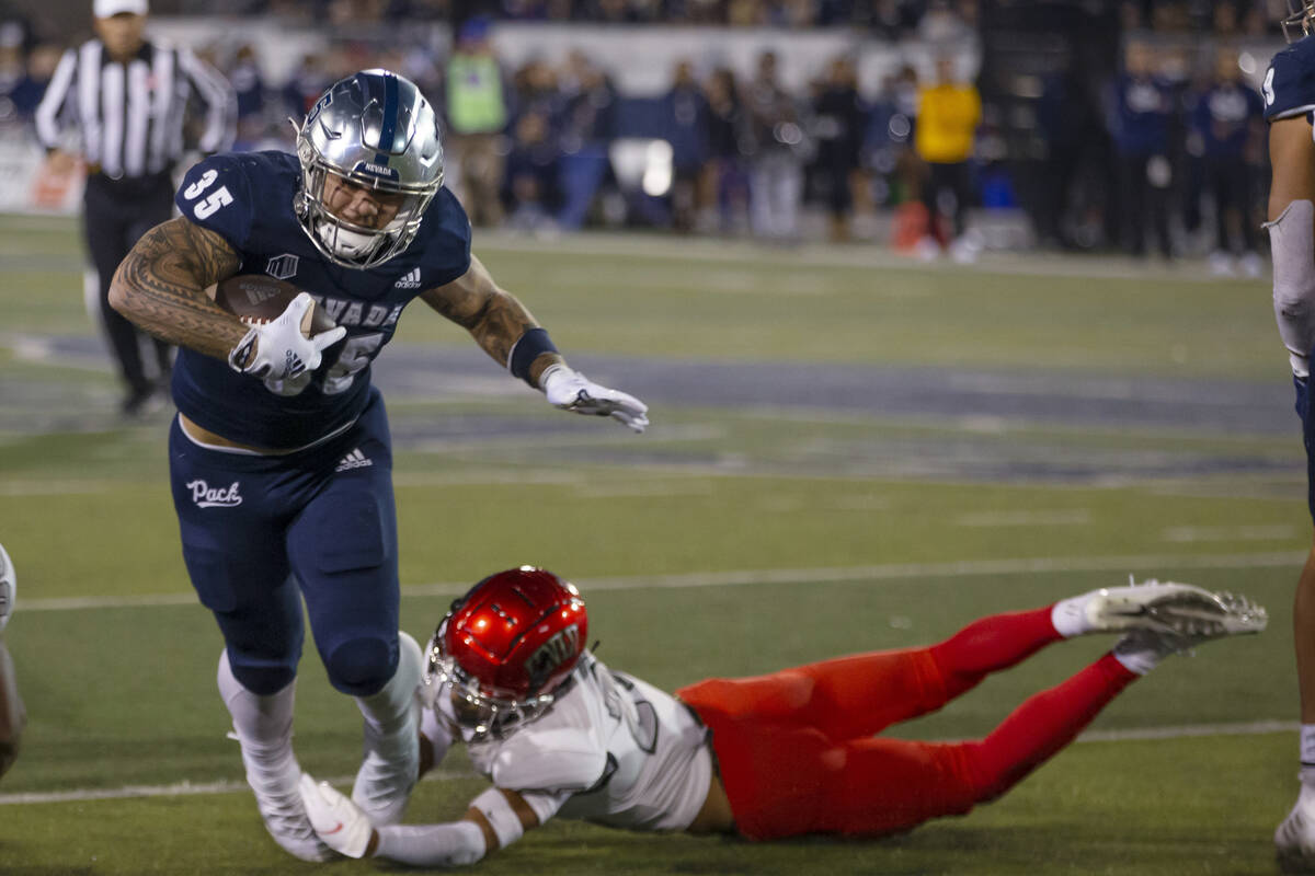 Nevada running back Toa Taua (35) is tackled by UNLV's Cameron Oliver (25) during the first hal ...