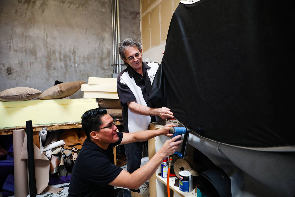 Upholster Santiago Hernandez, left, gets help from owner Glen Uslan, right, as he finishes up a ...