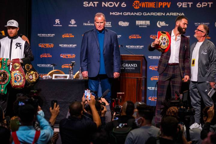 Boxer Canelo Alvarez holds his belts with trainer Eddy Reynoso, left, and Caleb Plant beside hi ...