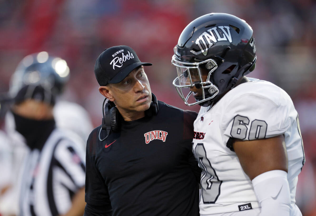 UNLV coach Marcus Arroyo listens to offensive lineman Amani Trigg-Wright during the first half ...