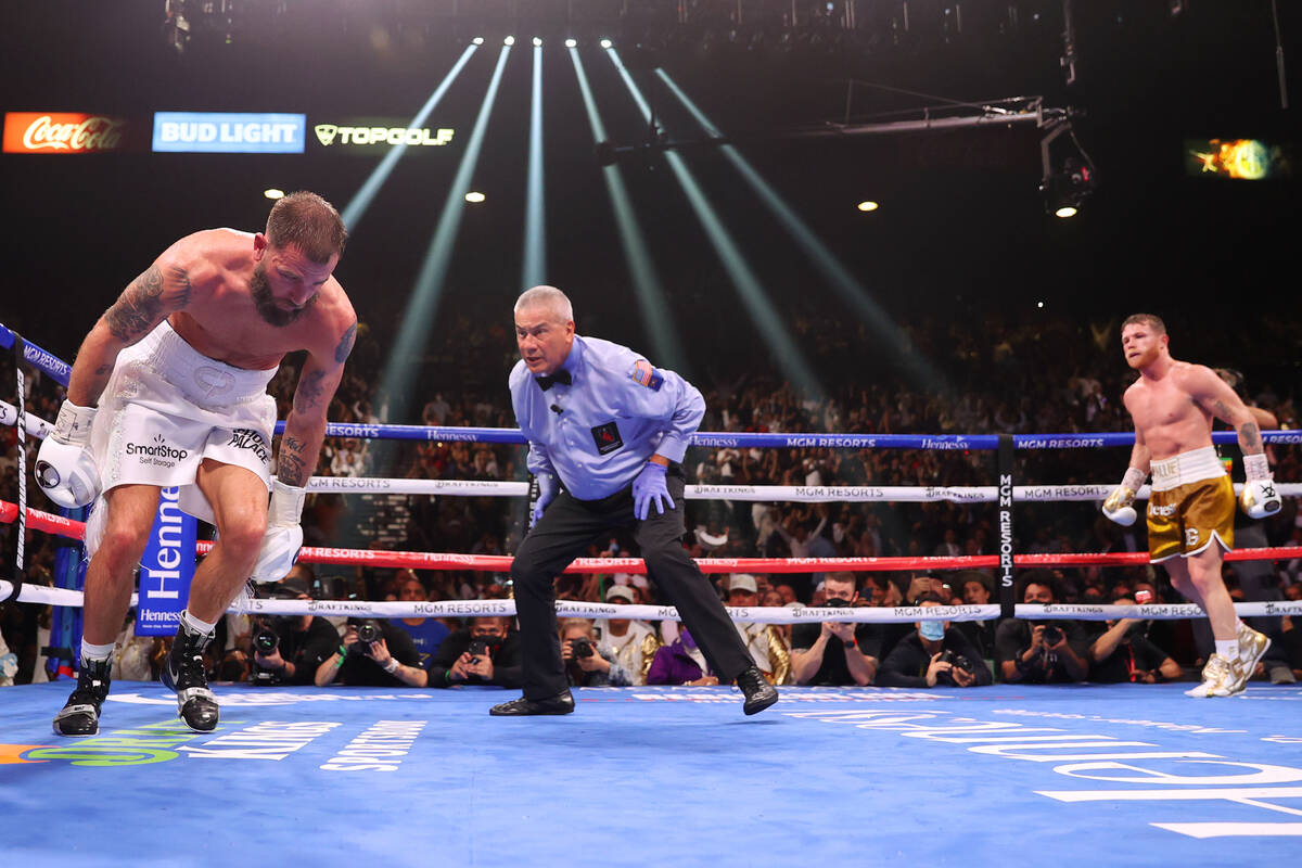 Saul “Canelo” Alvarez, right, watches as Caleb Plant stumbles after getting knock ...