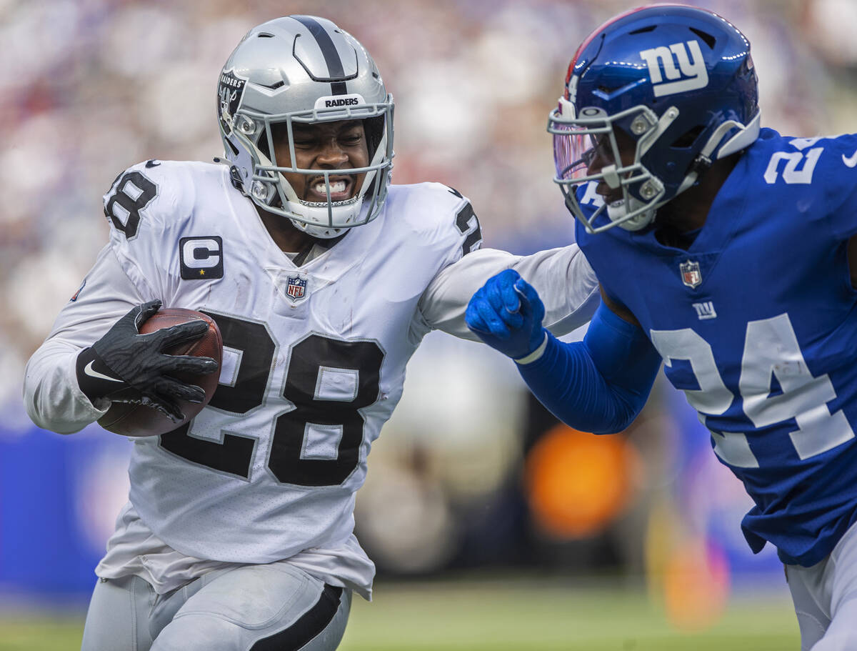 Las Vegas Raiders running back Josh Jacobs (28) stiff arms New York Giants cornerback James Bra ...