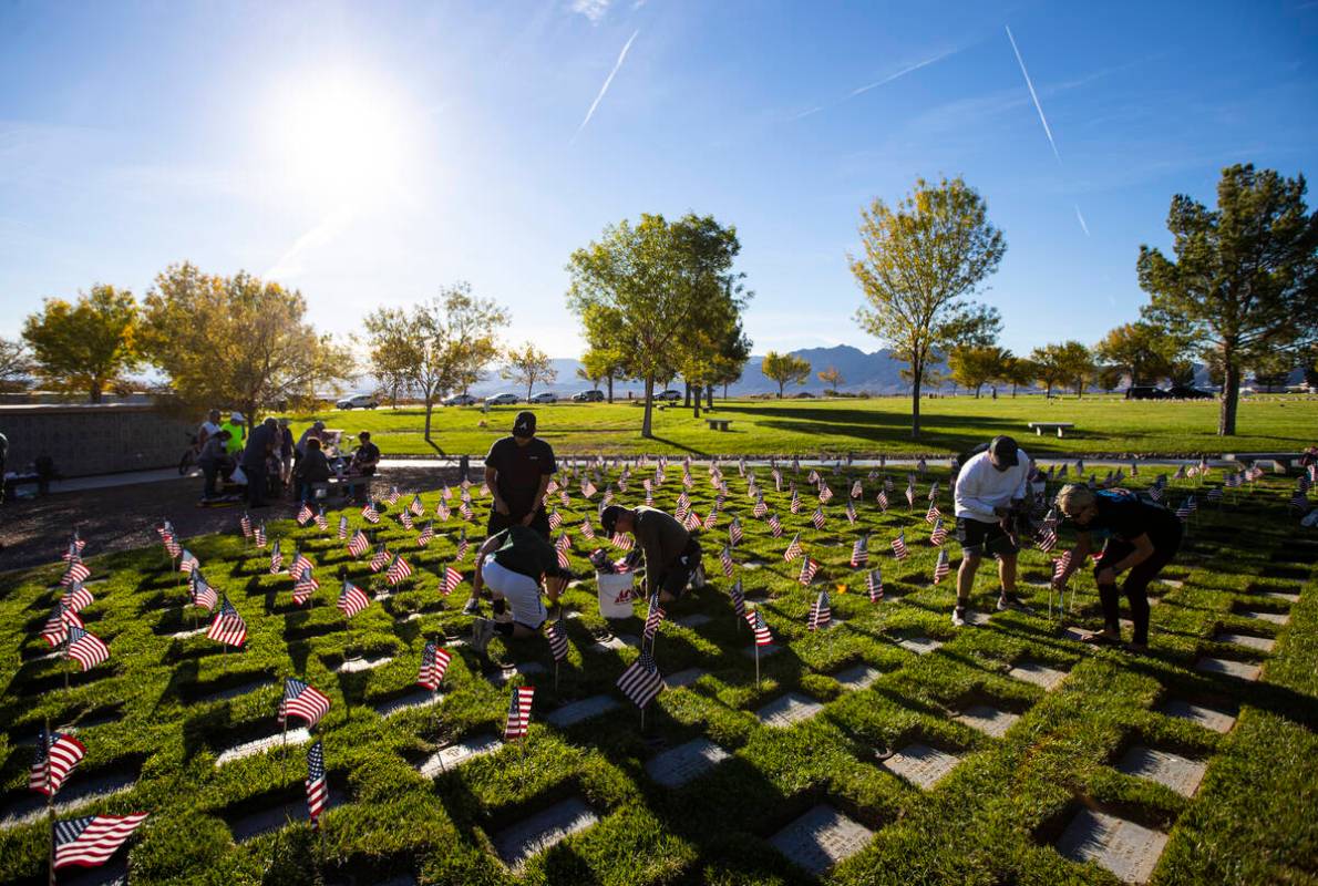 Volunteers place American flags on graves at the Southern Nevada Veterans Memorial Cemetery in ...