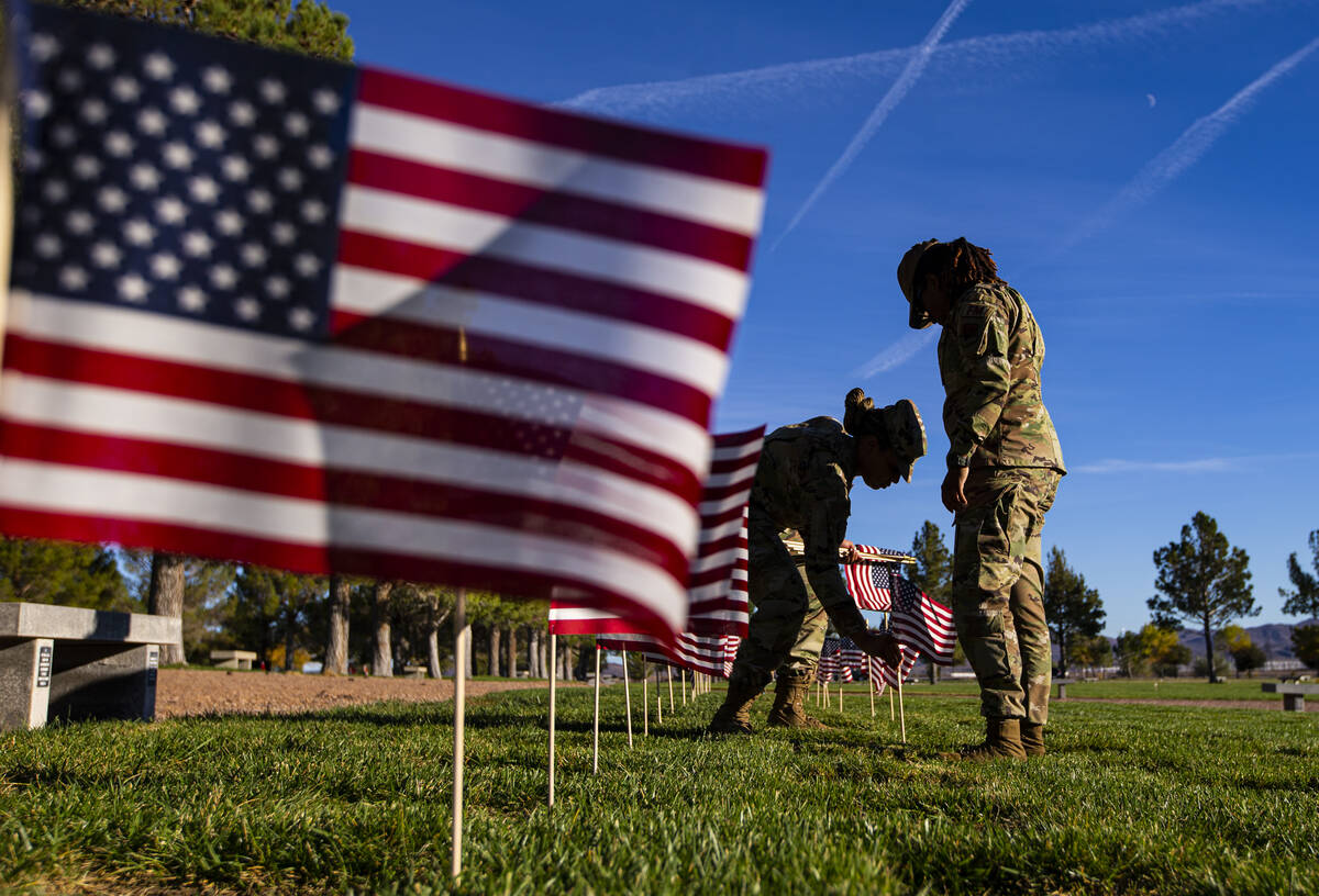Air Force Senior Airmen Shakira Jefferson, left, and Kayla Stephens place American flags on gra ...
