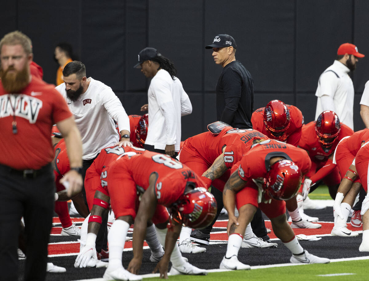 UNLV Rebels head coach Marcus Arroyo watches as his players stretch before an NCAA football gam ...