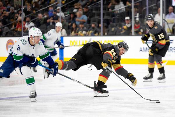 Golden Knights center Mattias Janmark (26) loses control of the puck as Canucks left wing Nils ...