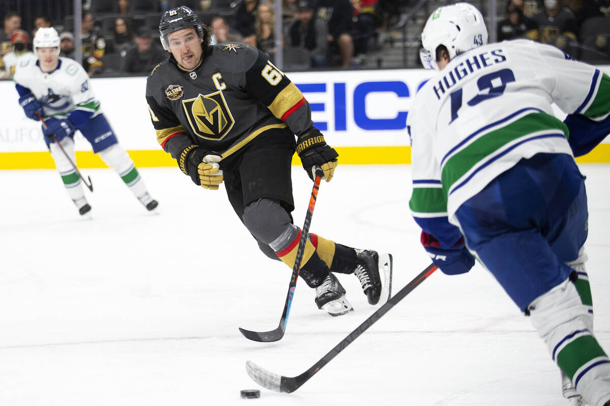 Golden Knights right wing Mark Stone (61) eyes the puck while Canucks defenseman Quinn Hughes ( ...