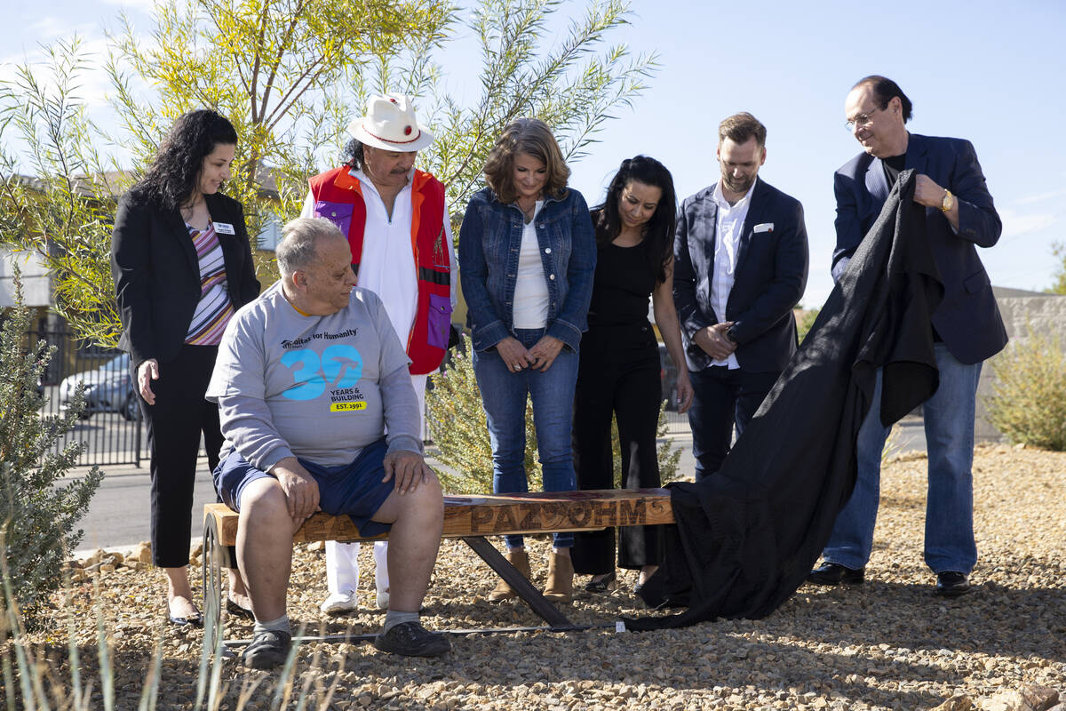 Reuben Nieves, sitting on the bench, watches as a specialty bench is unveiled outside of his ho ...