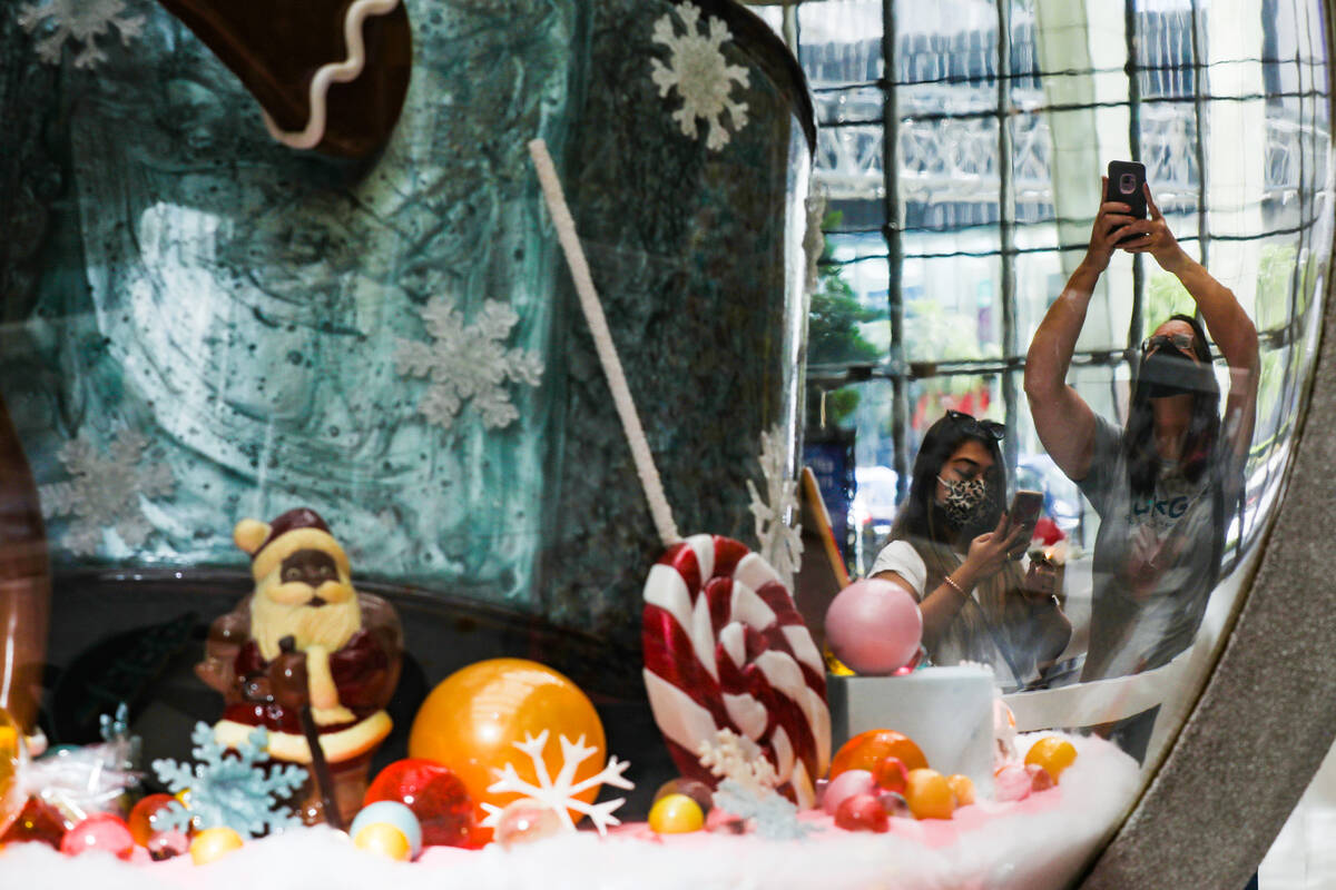 Onlookers take photos of the holiday display made of mostly candy that features an 8-foot-tall ...
