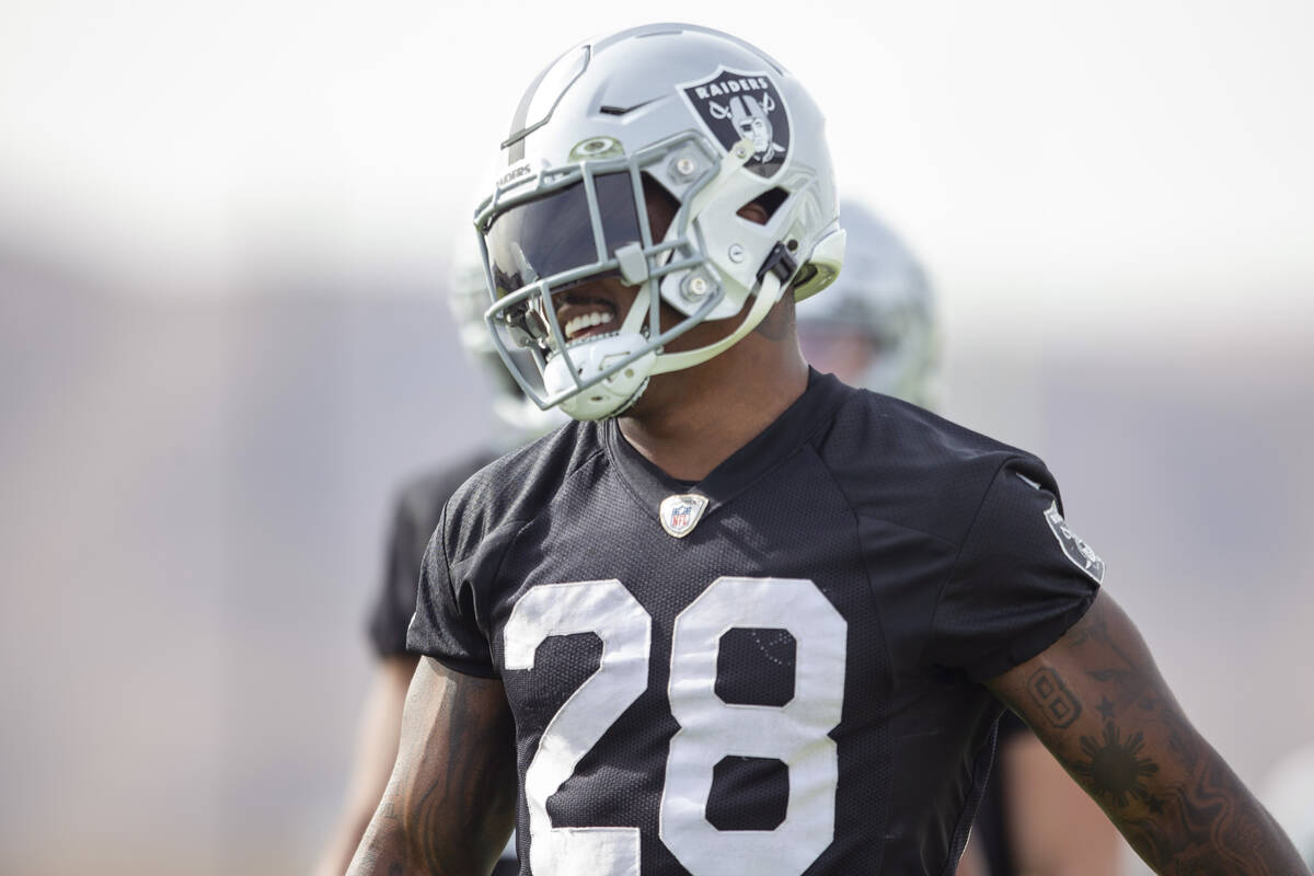 Raiders running back Josh Jacobs (28) walks on the field smiling during a practice session at R ...