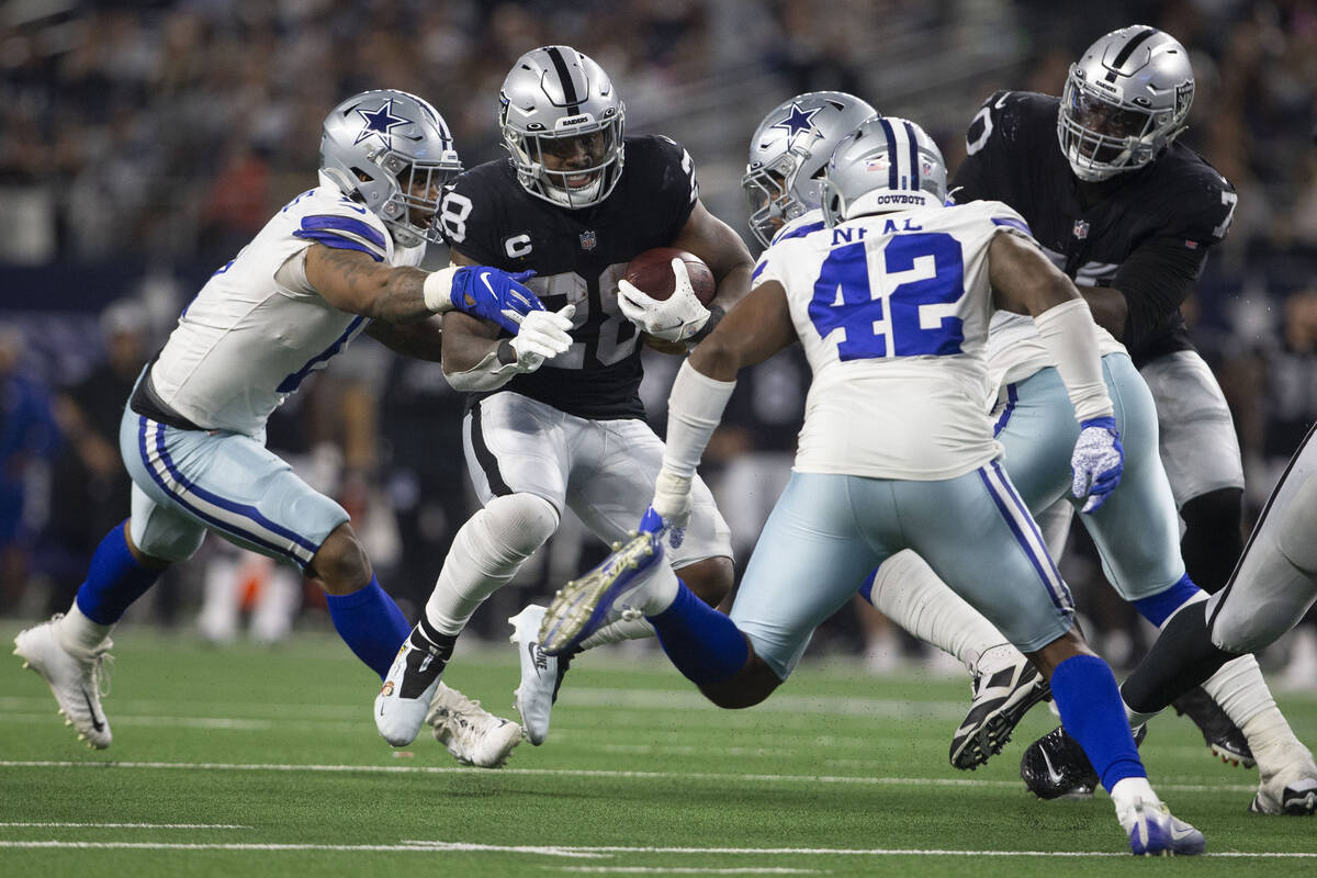 Raiders running back Josh Jacobs (28) looks for room to run against Dallas Cowboys outside line ...