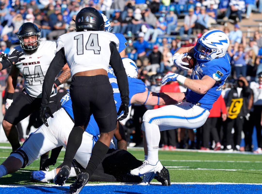 Air Force running back Brad Roberts, right, tumbles backward into the end zone for a touchdown ...