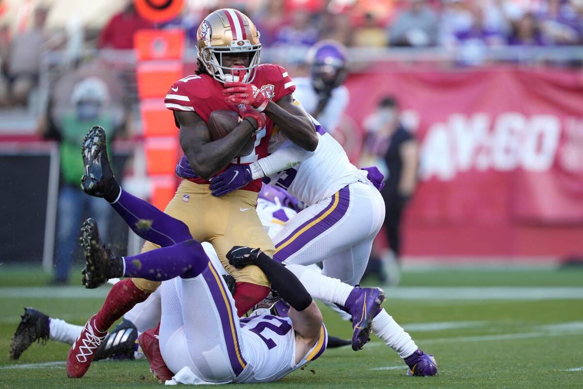 San Francisco 49ers wide receiver Brandon Aiyuk, top, is tackled by Minnesota Vikings safety Ha ...