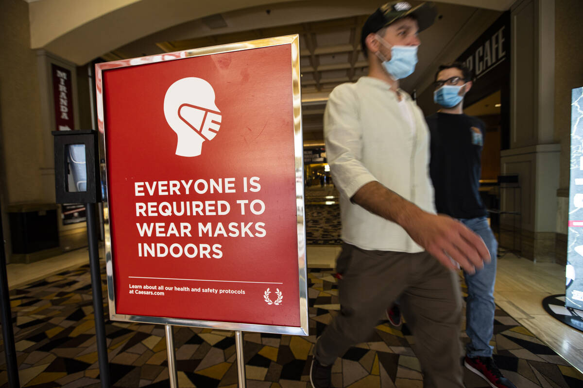 In this Oct. 28, 2021, file photo, people walk by a sign about indoor mask wearing at the World ...