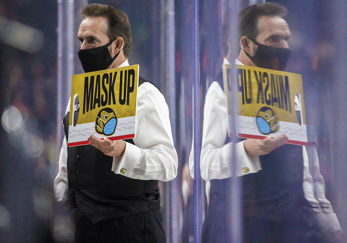 An usher holds a mask up sign during the Golden Knights Carolina Hurricanes NHL hockey game on ...