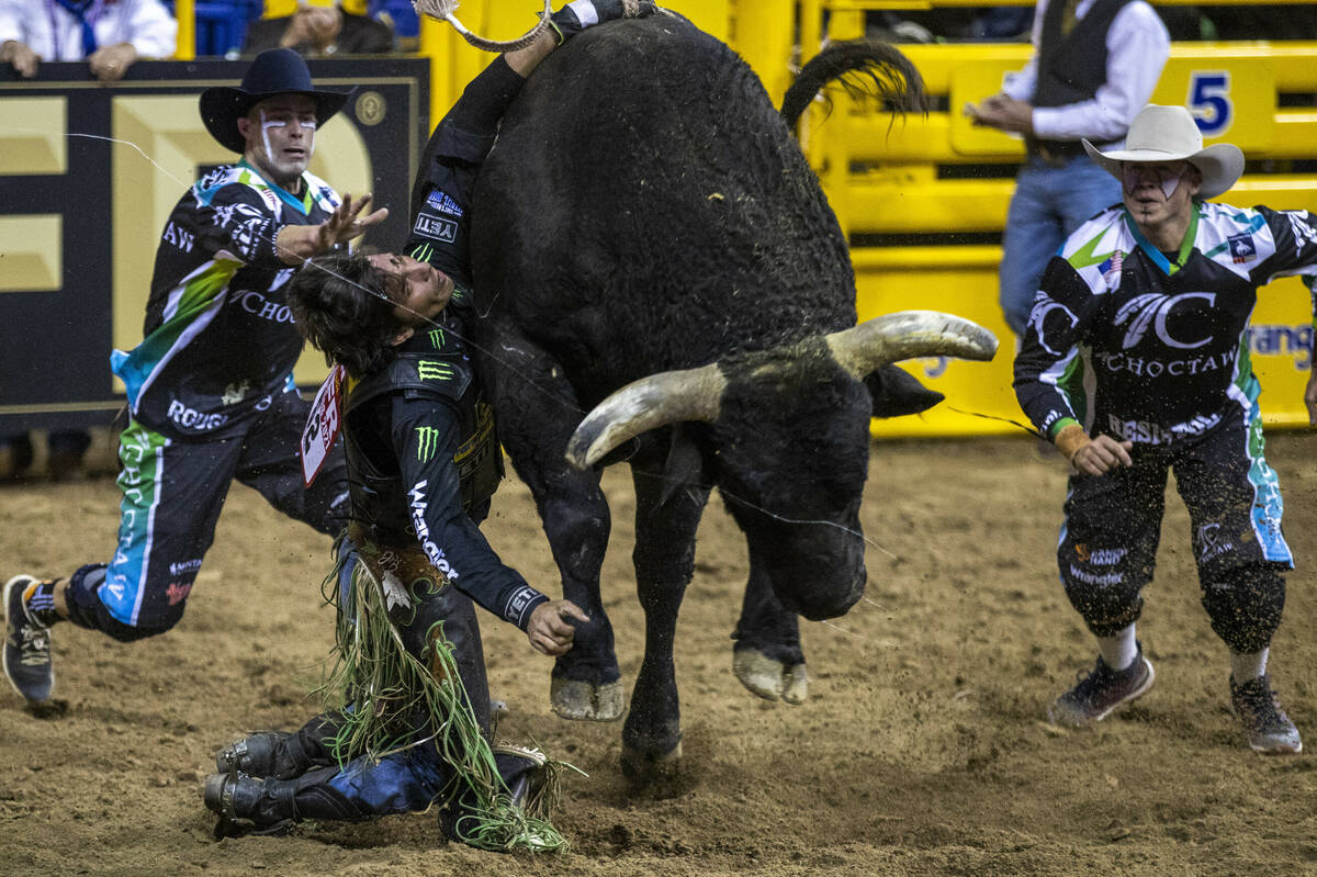 J.B. Mauney of Cotulla, TX., is dragged by Johnny Thunder in Bull Riding as bullfighters move i ...